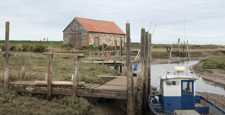 Photo of the quay at Thornham with a boat moored in the foreground