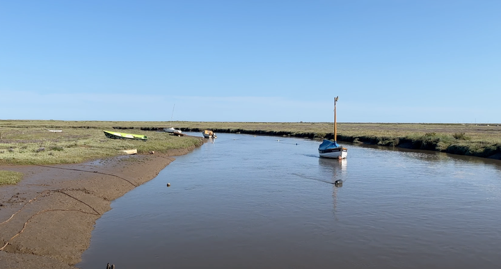 moored boat in an estuary with tidal salt marsh in the background